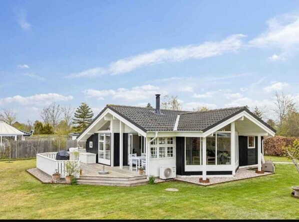 A two-story house with a covered patio, a chimney, and a fenced backyard.