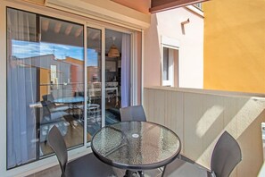 A balcony with a glass door, a round table, and two chairs.