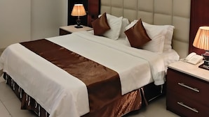 Une chambre d’hôtel moderne avec un grand lit, une table de chevet avec une lampe et une armoire intégrée.