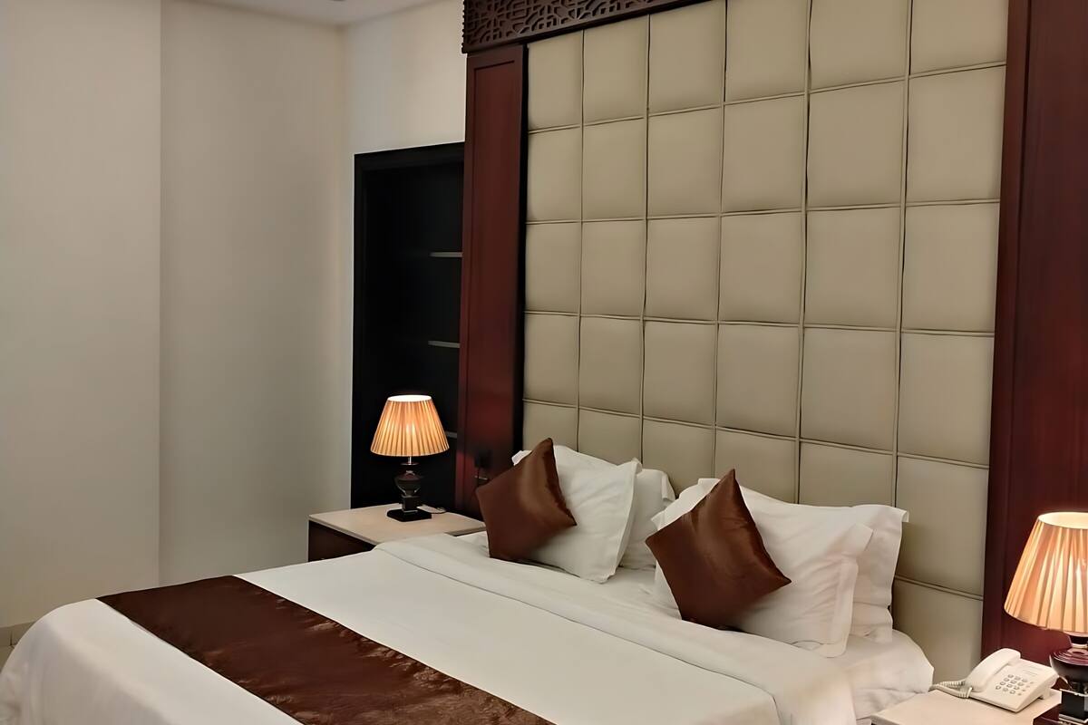 Ein modernes Hotelzimmer mit einem großen Bett, einem Nachttisch mit Lampe und einem eingebauten Kleiderschrank.