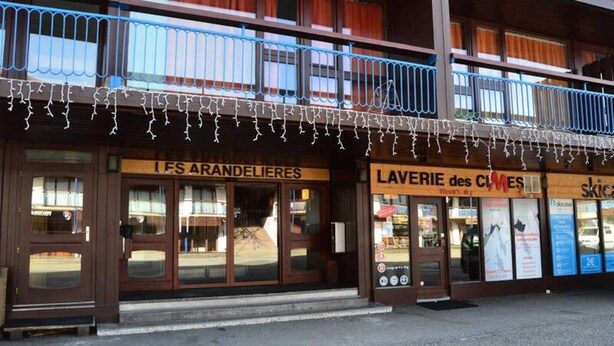 A building with storefronts including 'LES ARANDELIERES' and 'LAVERIE des CLIMES'. - Beautiful Duplex for 8 People, in the Heart of the Arc 1800 Resort With a Breathtaking View of the Valley (Bourg-Saint-Maurice)