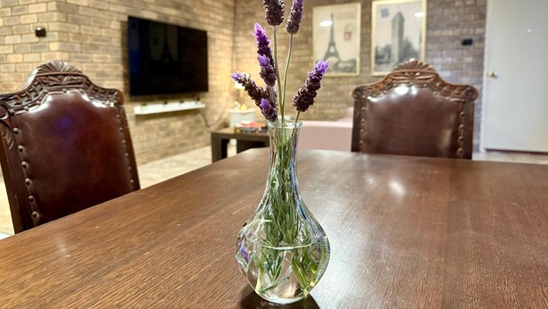 A dining table with a vase of lavender flowers in the center, surrounded by wooden chairs. - Spacious Villa with Comfortable Beds (Rangeway)