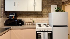 A kitchen with white cabinets, a brick wall, a Hisense coffee maker, a Hisense microwave, a Hisense stove, and a Hisense refrigerator. - Spacious Villa with Comfortable Beds (Rangeway)