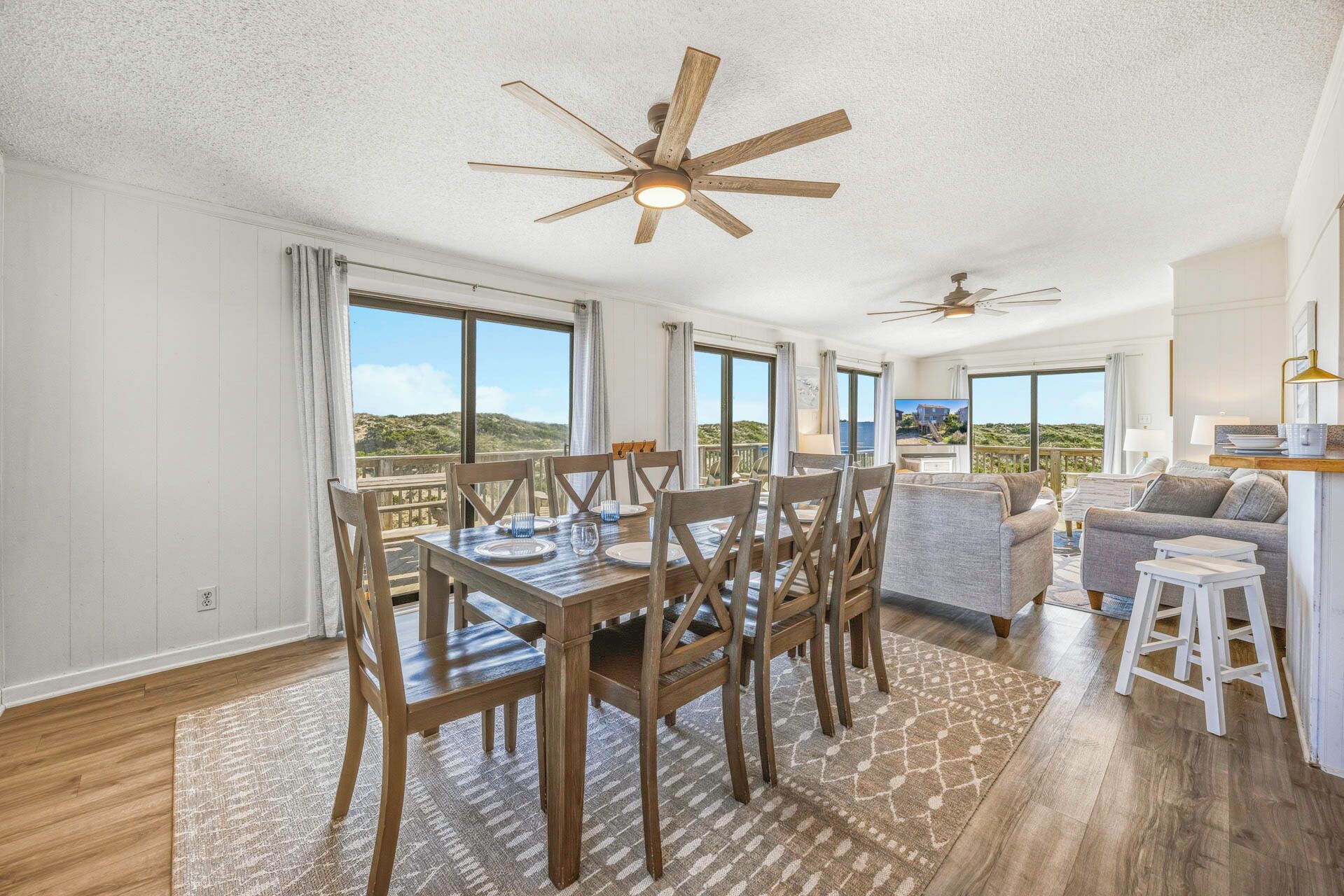 Un amplio espacio de sala con una mesa de comedor lista para cuatro personas, un sofá y un balcón con vistas.