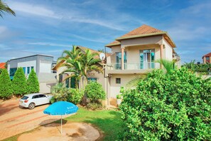 A two-story house with a balcony, surrounded by greenery and a parked car. - THELIGHT SUITES KIGALI (Kigali)