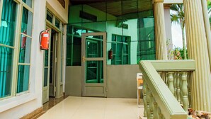 A building entrance with a wooden ceiling, a fire extinguisher, and a staircase leading to a door. - THELIGHT SUITES KIGALI (Kigali)