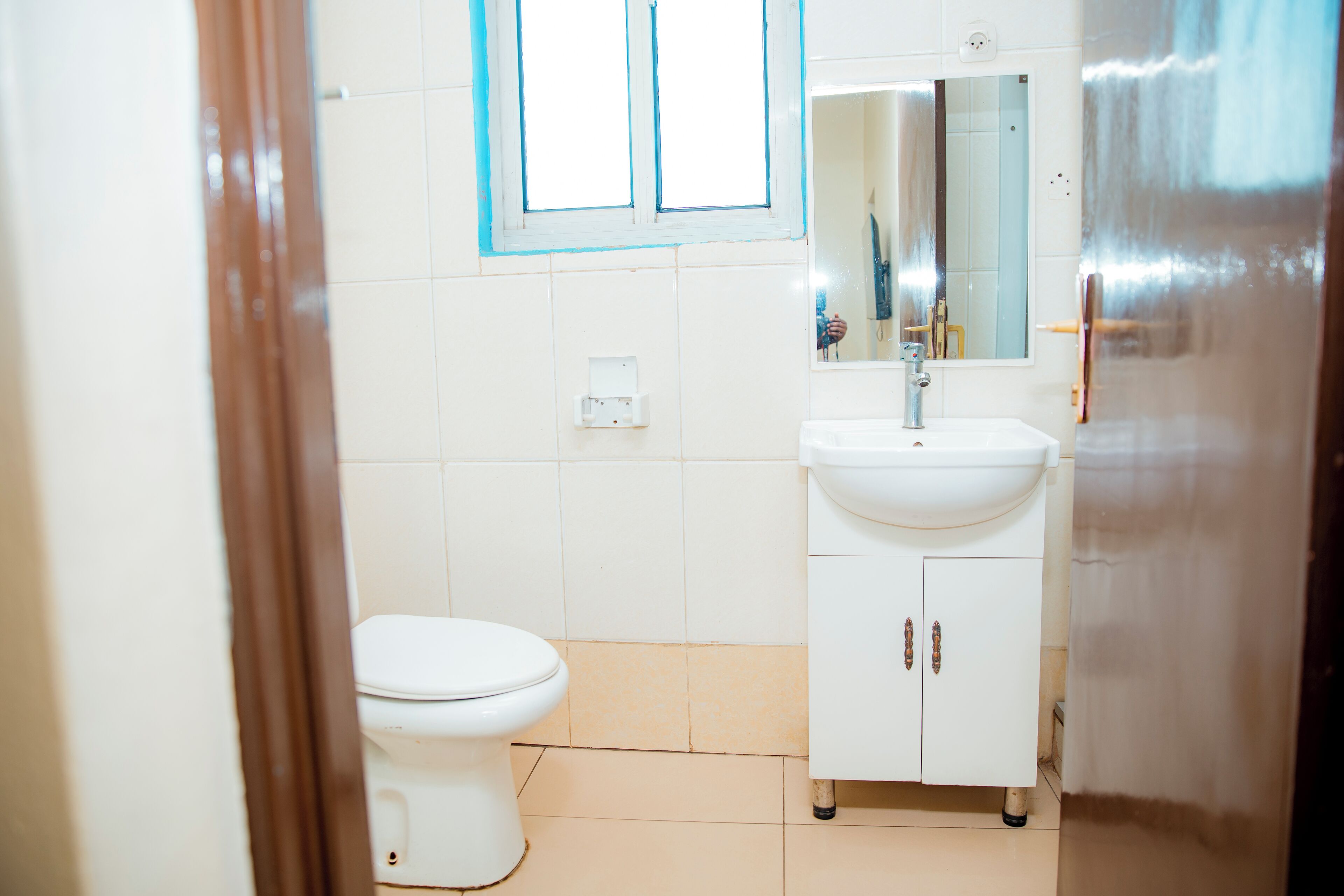 A bathroom with a toilet, sink, and mirror.