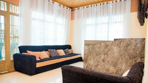 A modern living room with a dark blue sofa, a patterned rug, and a marble accent wall. - THELIGHT SUITES KIGALI (Kigali)