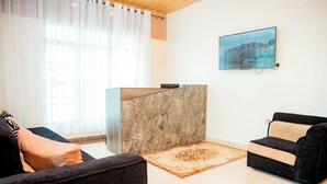 A modern reception area with a marble reception desk, two sofas, a patterned rug, and a framed picture on the wall. - THELIGHT SUITES KIGALI (Kigali)