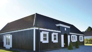 En toetagers bygning med mørk facade, hvidt dekoration og et skråt tag.