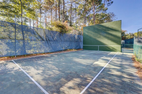 An outdoor tennis court with a green surface and white boundary lines. - Top Floor Ocean View! | Island Club 1502 (Hilton Head Island)