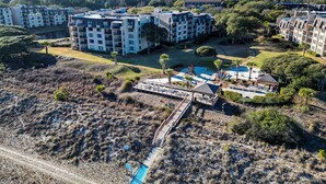 An aerial view of a residential complex with multiple apartment buildings, a playground, and a swimming pool. - Top Floor Ocean View! | Island Club 1502 (Hilton Head Island)