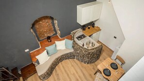 Une cuisine compacte avec un mur d’accent en pierre, une cuisinière intégrée et un petit coin repas comprenant une table et des chaises en bois.