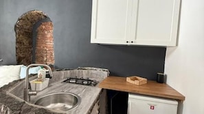 A kitchen with a sink, a gas stove, a cabinet, and a brick wall. - 200m Monastero Benedettini Loft in historic center (Catania)