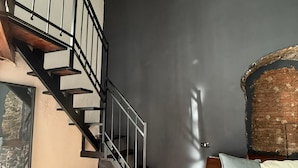 A modern interior with a staircase, a stone wall, and a sofa with cushions. - Jesuit Home - Lumina Collection (Catania)