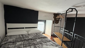 A bedroom with a large bed, a bunk bed, a window, and a hanging light fixture. - Jesuit Home - Lumina Collection (Catania)