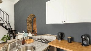 A kitchen with a stone countertop, a gas stove, a sink, and a coffee machine.