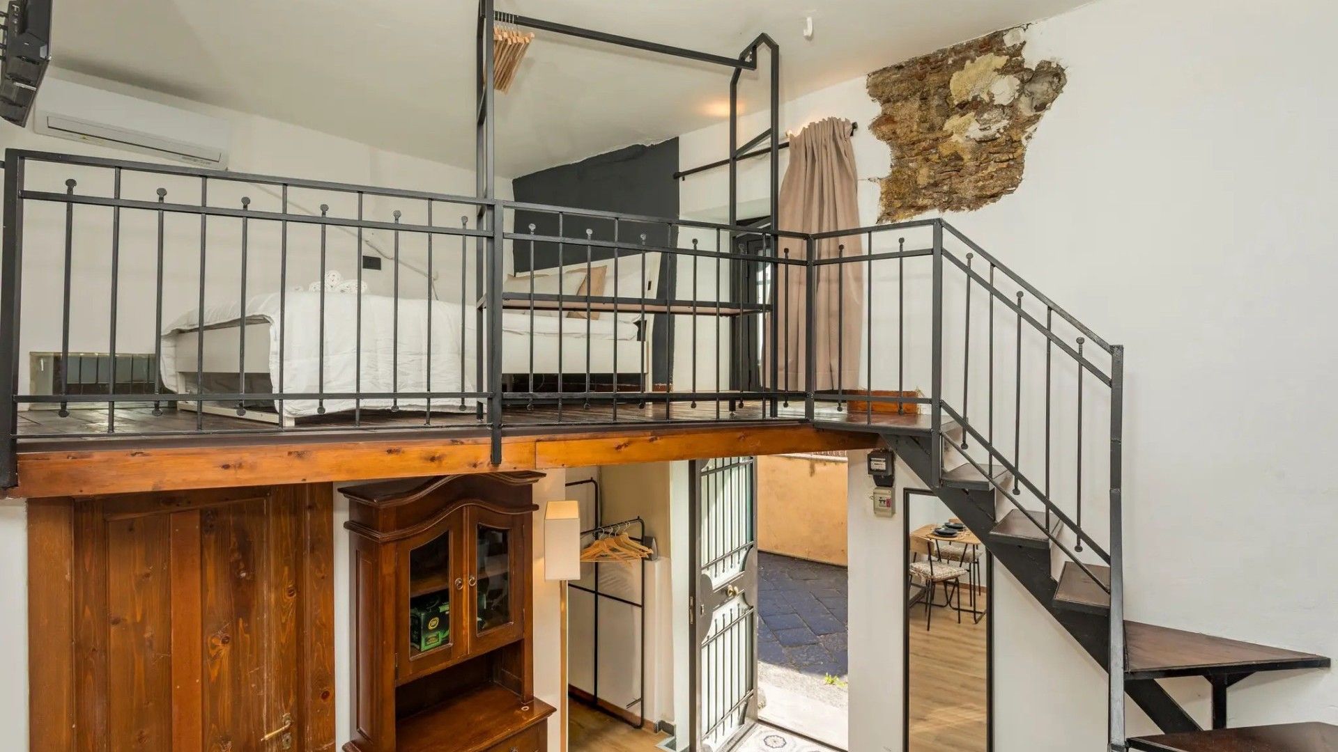 A multi-level interior with a wooden staircase, metal railings, and a stone wall feature.