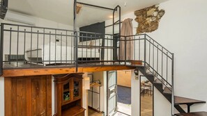 A multi-level interior with a wooden staircase, metal railings, and a stone wall feature.