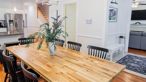 A modern kitchen with stainless steel appliances, a wooden dining table with chairs, and a staircase leading to another level. - Historic Westend Jewel-Pet Friendly, Sleeps 12 (Atlanta)
