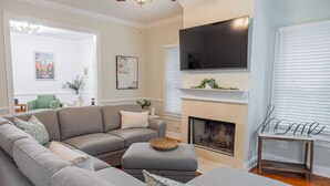 A living room with a sectional sofa, a fireplace, a television, and a chair. - Historic Westend Jewel-Pet Friendly, Sleeps 12 (Atlanta)