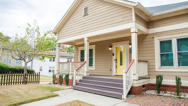 A two-story house with a front porch, a yellow door, and a brick foundation. - Historic Westend Jewel-Pet Friendly, Sleeps 12 (Atlanta)
