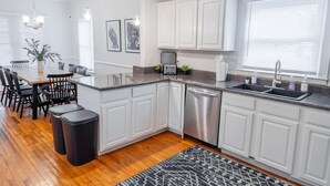 A modern kitchen with white cabinets, a stainless steel dishwasher, and a granite countertop. - Historic Westend Jewel-Pet Friendly, Sleeps 12 (Atlanta)