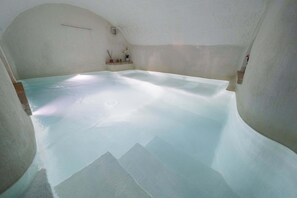 A room with a large, clear bathtub, a small shelf with decorative items, and a sloped ceiling. - Amazing Apartment "Alla Corte" with pool and sauna (Taurisano)
