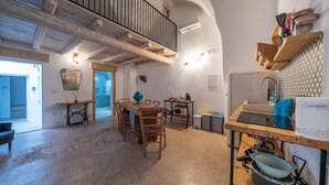 Uma cozinha espaçosa com vigas de madeira, uma área de jantar com mesa e cadeiras, e uma varanda com guarda-corpo.