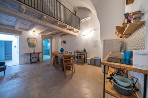 A spacious kitchen with wooden beams, a dining area with a table and chairs, and a balcony with a railing. - Amazing Apartment "Alla Corte" with pool and sauna (Taurisano)