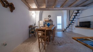 Cozinha espaçosa com mesa e cadeiras de madeira, geladeira e um relógio na parede.