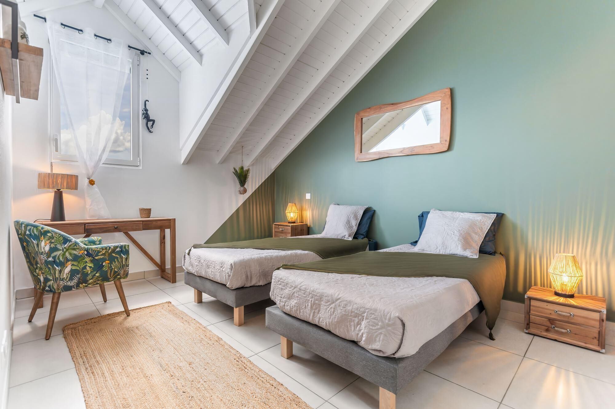 A bedroom with two beds, a desk, a chair, and a mirror on the wall.