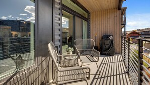 A balcony with wicker chairs, a wooden ceiling, and a view of the surrounding area. - Newly Constructed Condo along the Blue River (Silverthorne)