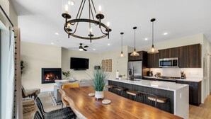 A modern kitchen with a central island, dark wooden cabinets, a built-in microwave, and pendant lighting. - Newly Constructed Condo along the Blue River (Silverthorne)