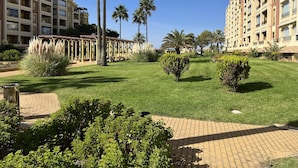 A courtyard with palm trees, a pergola, and a well-maintained lawn. - CANELA BEACH DREAM, PENTHOUSE ON THE SEA (Isla Canela)