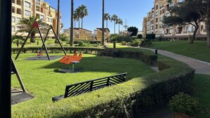 A park with a swing set, benches, and a well-maintained lawn. - CANELA BEACH DREAM, PENTHOUSE ON THE SEA (Isla Canela)
