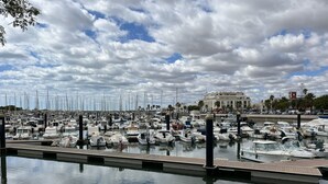 A marina with numerous boats docked, a clear sky, and a building in the background. - CANELA BEACH DREAM, PENTHOUSE ON THE SEA (Isla Canela)