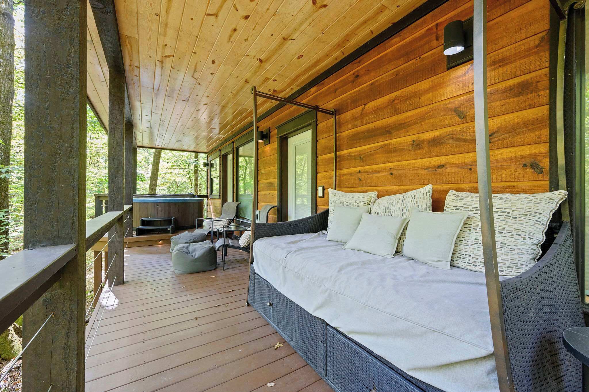 A wooden cabin with a large bed, a seating area, and a hot tub.