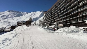 A snow-covered ski slope with a modern hotel building on the right. - Apartment in Tignes With Mountain Views (Tignes)