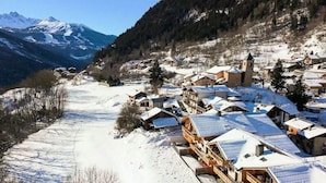 A snow-covered village with traditional wooden houses, a church, and a mountain in the background. - 4 Rooms for 8 People (Champagny-en-Vanoise)