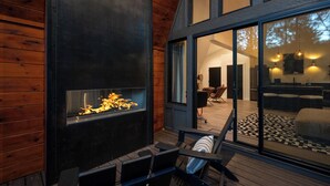 A modern interior with a fireplace, wooden walls, and a large window overlooking a living area. - A Place and Time Blue Ridge GA (Blue Ridge)