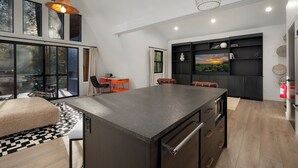 A modern kitchen with a large island, black cabinets, and a dining area with a table and chairs. - A Place and Time Blue Ridge GA (Blue Ridge)