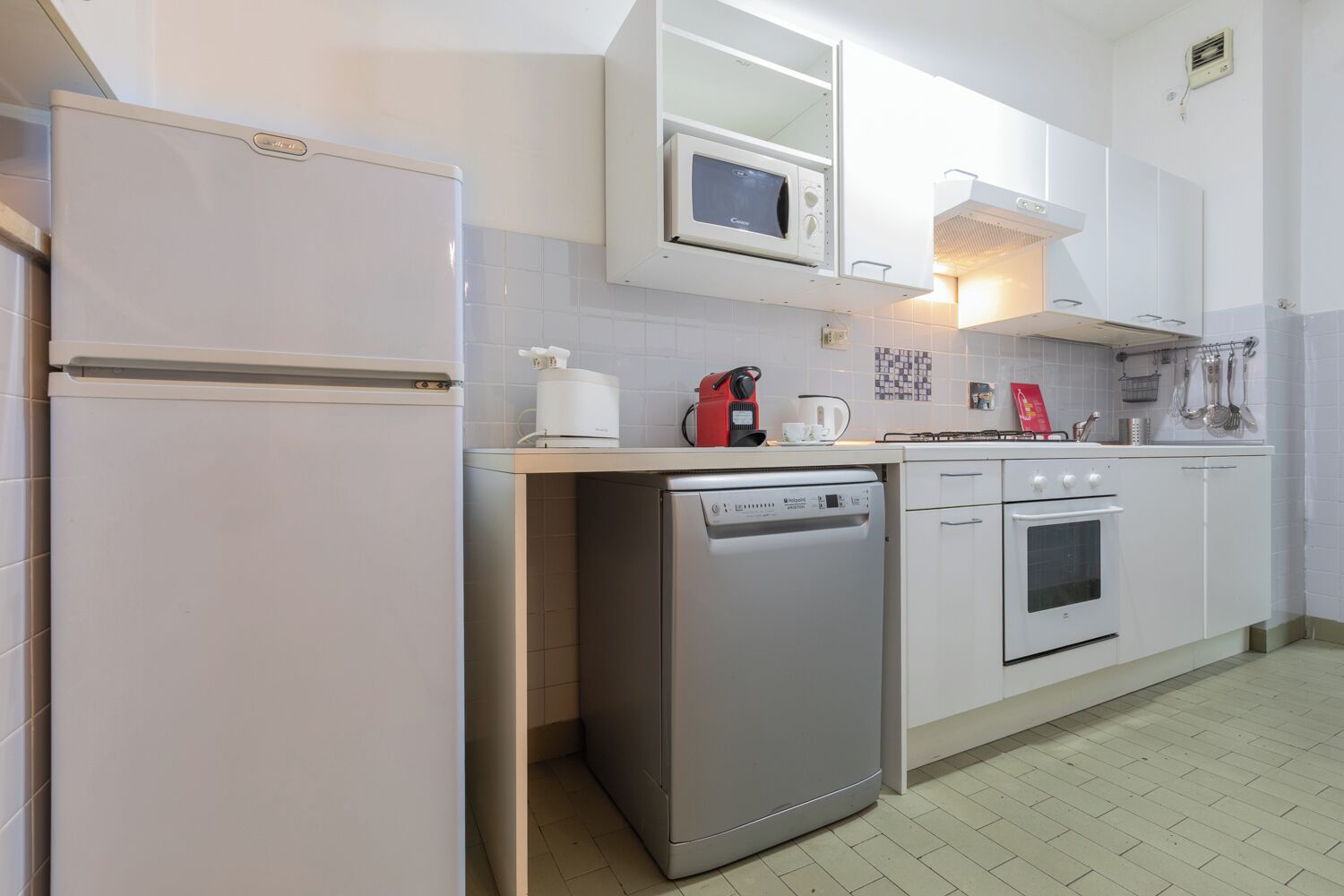 A compact kitchen with a refrigerator, microwave, coffee maker, dishwasher, stove, and oven.