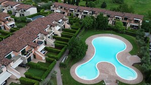 A residential complex with a central swimming pool, multiple balconies, and well-maintained gardens.