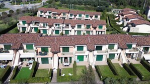 A residential complex with multiple two-story houses, each with a balcony and a green door.