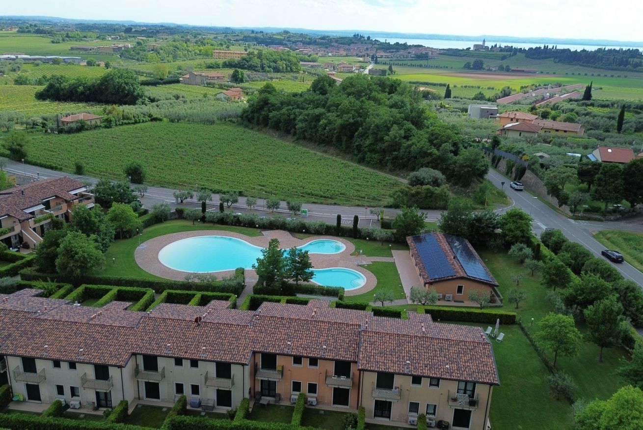 A residential area with a swimming pool, terraced houses, and surrounding greenery.