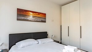 A hotel room with a bed, a nightstand, a wall-mounted painting, and a wardrobe.