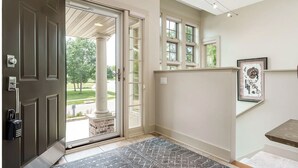 Un hall d’entrée propre et moderne, avec une porte sombre, une porte vitrée donnant sur l’extérieur et un petit tapis sur le sol.