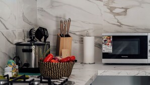 A modern kitchen with a microwave, stove, and a basket of red peppers. - VILLA LAZUREA located in the heart of Terre-Sainte on the main avenue (Saint-Pierre)