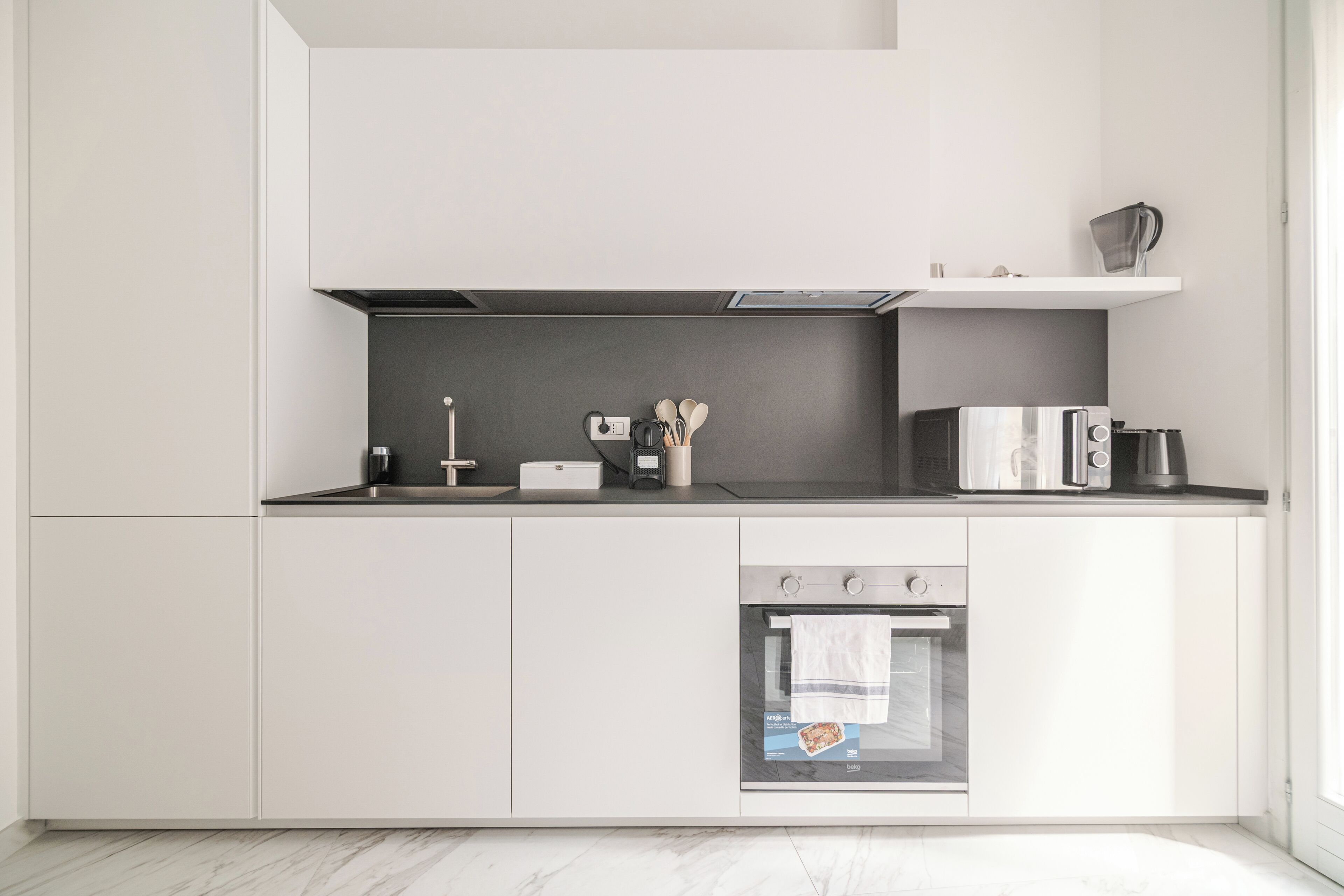 A modern kitchen with white cabinetry, a built-in oven, and a microwave.